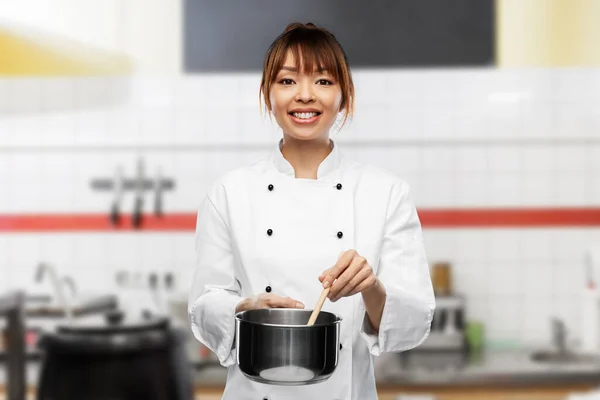 Happy female chef with saucepan over kitchen — Fotografia de Stock