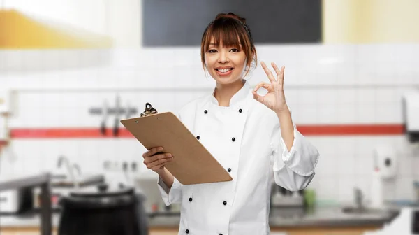 Smiling female chef with clipboard showing ok — ストック写真