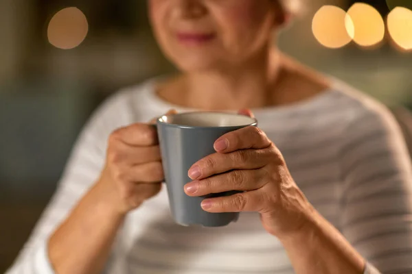 Крупним планом старша жінка з чашкою чаю вдома — стокове фото