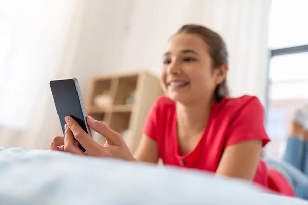 Sorridente ragazza adolescente sms su smartphone a casa — Foto Stock