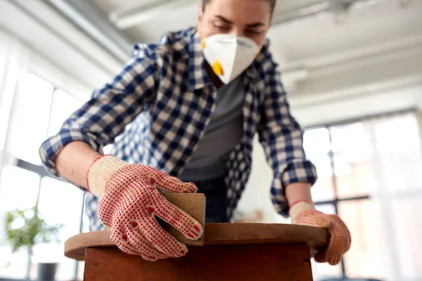 Woman in respirator sanding old table with sponge — Stock Photo, Image