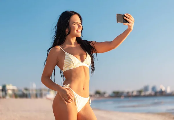 Lächelnde Frau im Bikini macht Selfie am Strand — Stockfoto