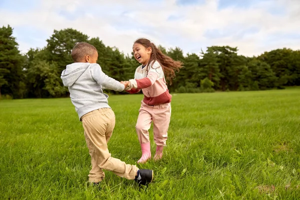 Fröhliche kleine Jungen und Mädchen, die Spaß im Park haben — Stockfoto