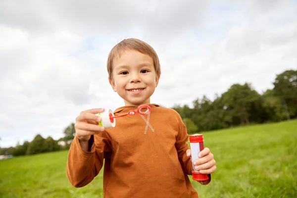 Menino brincando com bolhas de sabão no parque — Fotografia de Stock