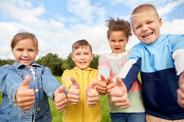 Glada barn visar tummen upp i parken — Stockfoto