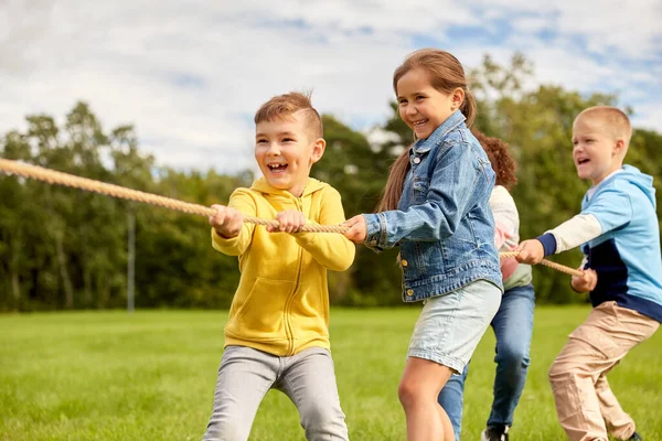 Niños felices jugando tirón de juego de guerra en el parque —  Fotos de Stock