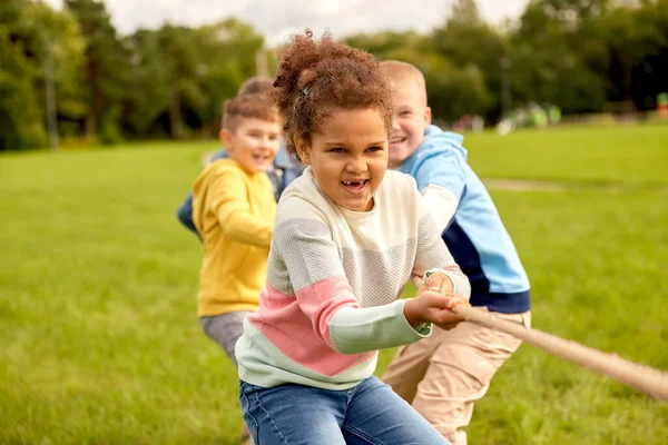 Happy children playing tug-of-war game at park Stock Image