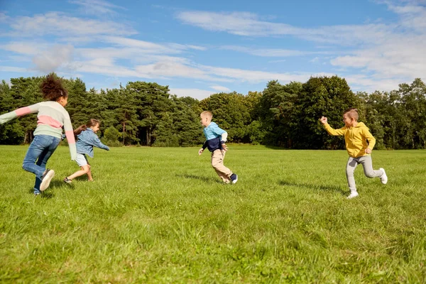 Glückliche Kinder spielen und rennen im Park — Stockfoto