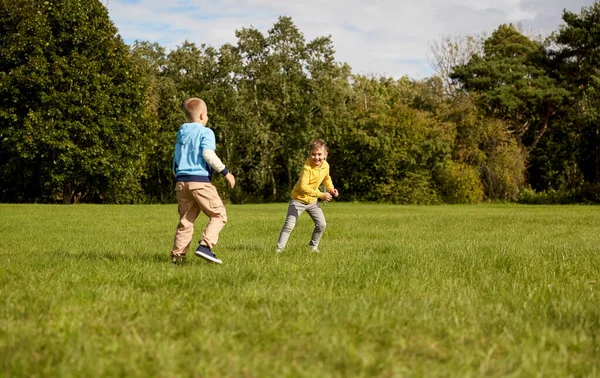 Šťastní kluci hrají a běží v parku — Stock fotografie