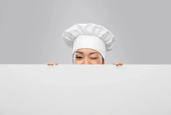 Chef feminino espreitando por trás da tábua branca — Fotografia de Stock