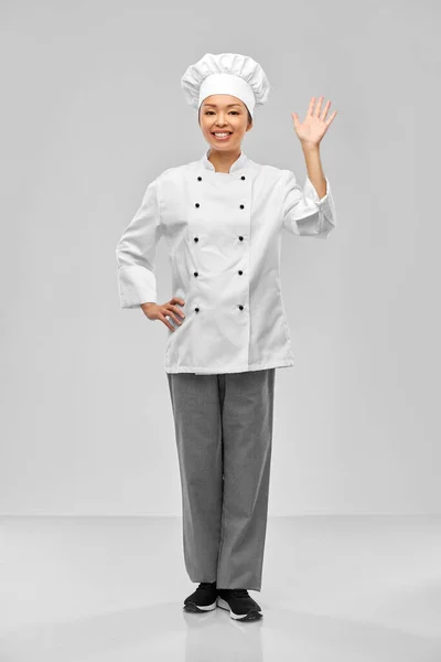 Smiling female chef waving hand — Zdjęcie stockowe