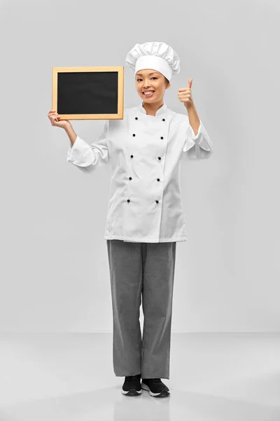 Female chef with chalkboard showing thumbs up — Stock Photo, Image