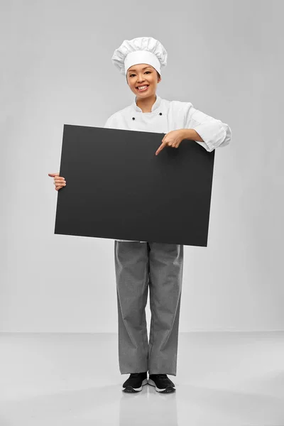 Smiling female chef holding black chalkboard — Stock Photo, Image