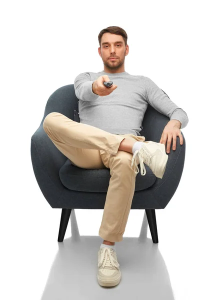 Man with tv remote control sitting in chair — Stockfoto