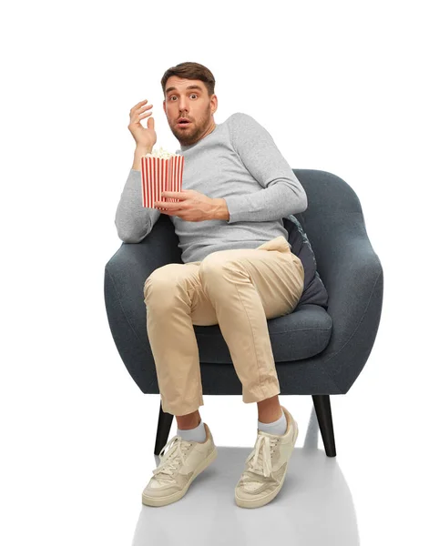 Scared man with popcorn sitting in chair — Stockfoto