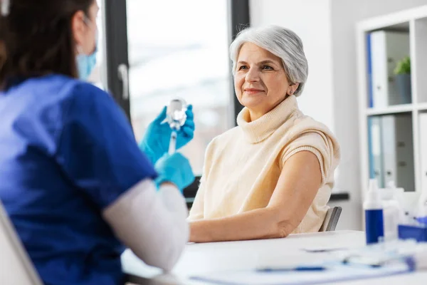 Şırıngalı bir doktor ve hastanede yaşlı bir kadın. — Stok fotoğraf