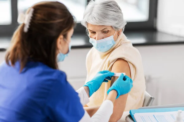 Verpleegkundige die medische pleisters op gevaccineerde vrouwen aanbrengt — Stockfoto