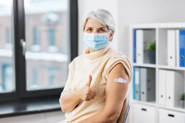 Donna vaccinata in maschera con cerotto medico sul braccio — Foto Stock