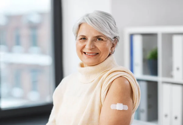Glimlachende gevaccineerde vrouw met medische pleister op de arm — Stockfoto