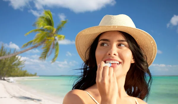 Mujer sonriente en bikini con bálsamo labial en la playa — Foto de Stock