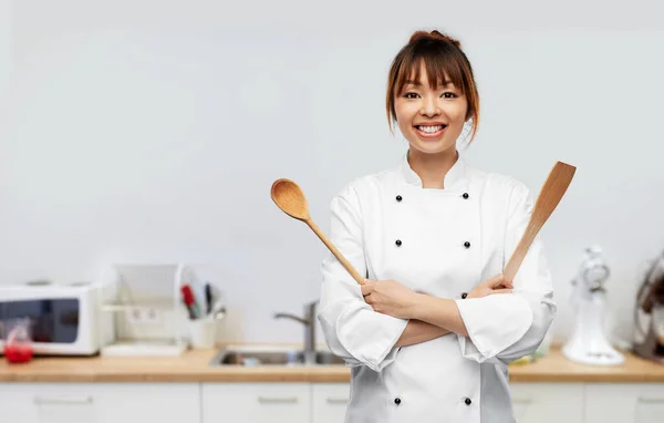 Happy female chef with wooden spoon on kitchen —  Fotos de Stock