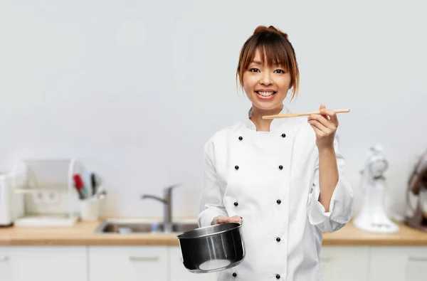 Female chef with saucepan tasting food on kitchen — Zdjęcie stockowe