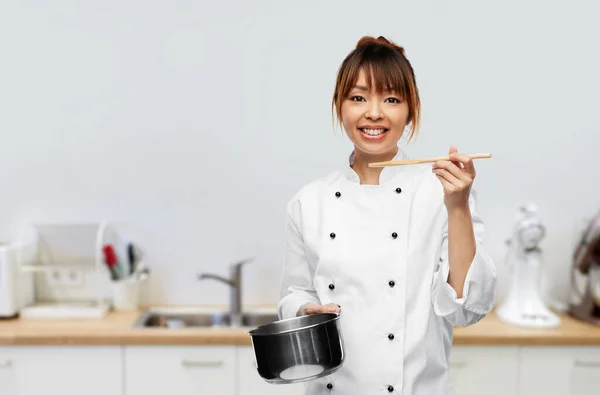 Female chef with saucepan tasting food on kitchen — стоковое фото