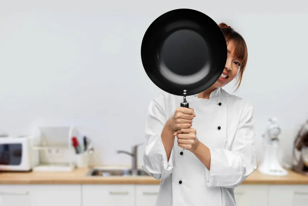 Chef peeking out from behind frying pan on kitchen — Fotografia de Stock