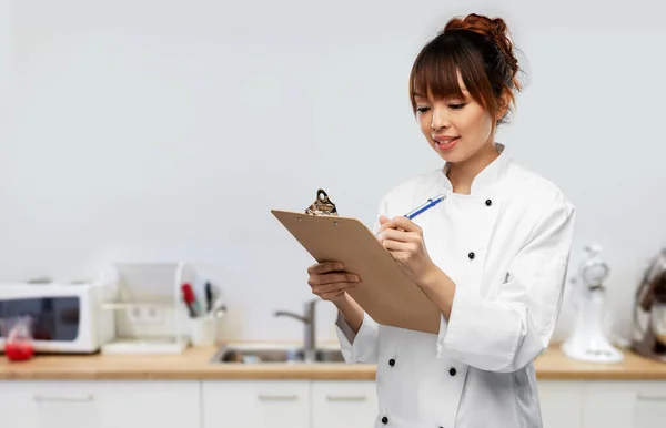 Chef femenino con portapapeles y pluma en la cocina — Foto de Stock