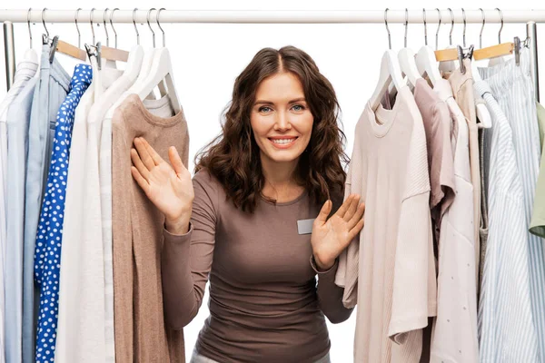 happy female shop assistant with clothes on hanger