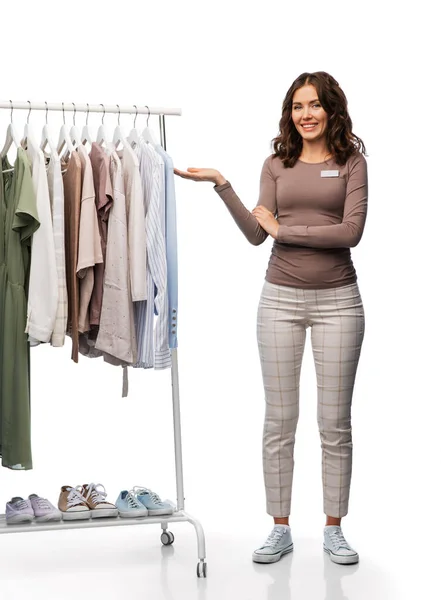 Asistente de tienda femenina feliz con ropa en percha —  Fotos de Stock