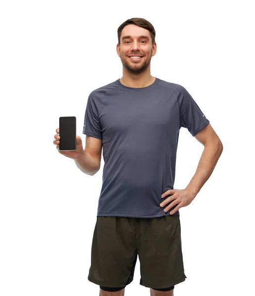 Spor elbiseli gülümseyen adam akıllı telefon gösteriyor. — Stok fotoğraf