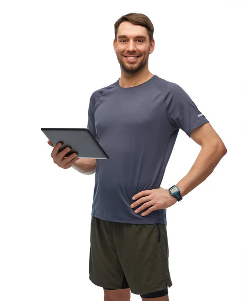 Улыбающийся человек в спортивной одежде с планшетным ПК — стоковое фото