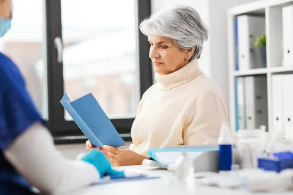 Doctor y mujer mayor leyendo folleto médico —  Fotos de Stock