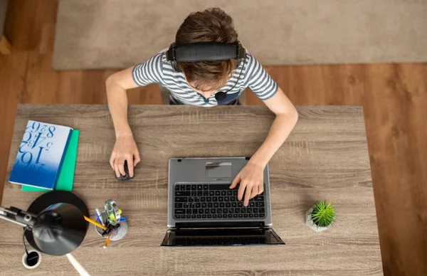 Menino em fones de ouvido usando laptop em casa — Fotografia de Stock