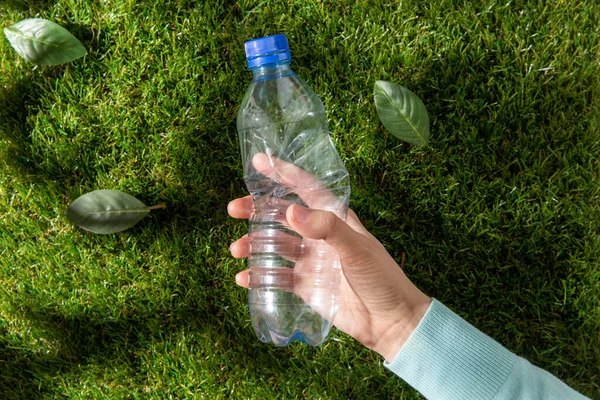 El, çimenden plastik şişeyi kaldırıyor. — Stok fotoğraf