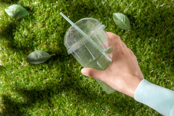 Gros plan de la main enlever la tasse en plastique de l'herbe — Photo