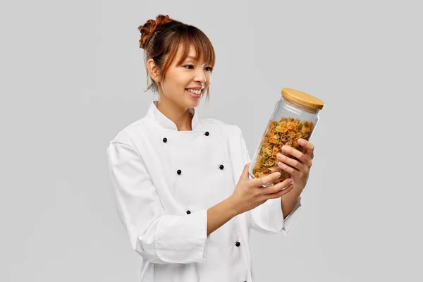 Smiling female chef holding jar with pasta — Stock Photo, Image