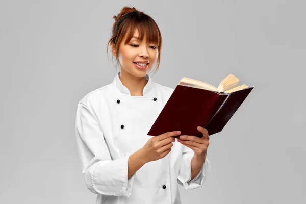 Sorridente chef feminino leitura livro cozinheiro — Fotografia de Stock