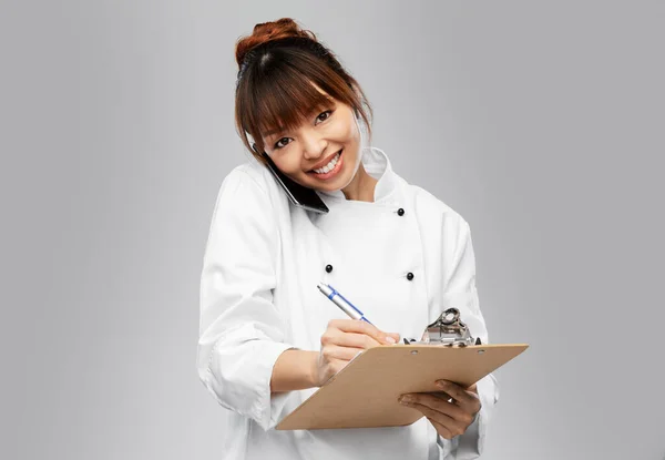 Chef feminino feliz com prancheta chamando no telefone — Fotografia de Stock