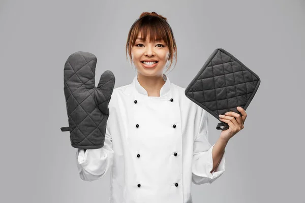 Chef mujer sonriente en chaqueta con agarraderas —  Fotos de Stock