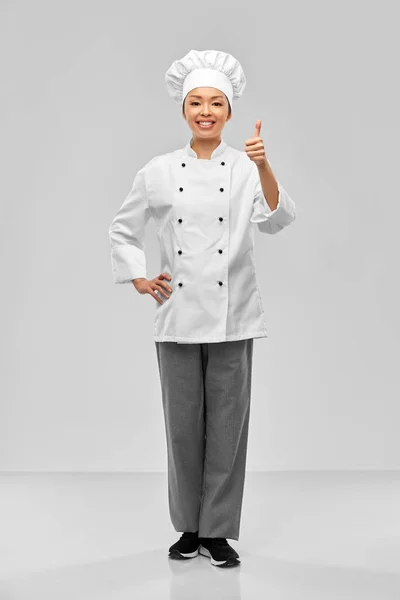 Sonriente mujer chef en chaqueta mostrando los pulgares hacia arriba —  Fotos de Stock