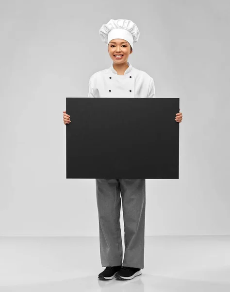 Sorridente chef donna con lavagna nera in mano — Foto Stock