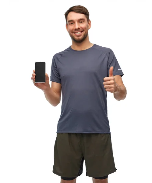 Χαμογελαστός άνδρας με αθλητικά ρούχα που δείχνει smartphone — Φωτογραφία Αρχείου