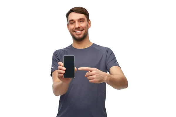 Sorrindo homem em roupas esportivas mostrando smartphone — Fotografia de Stock