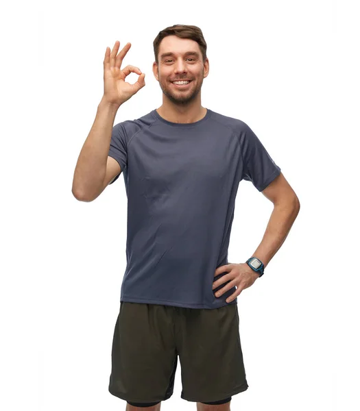 Hombre sonriente con reloj inteligente que muestra signo ok — Foto de Stock