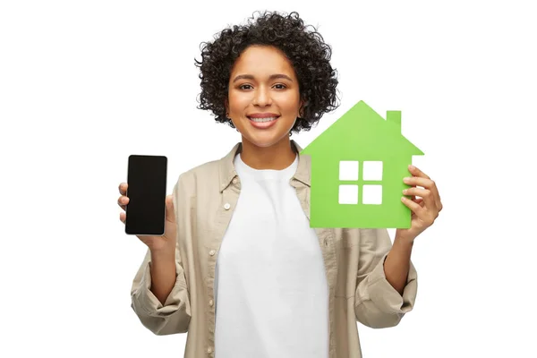 Sonriente mujer sosteniendo casa verde y teléfono inteligente —  Fotos de Stock