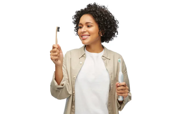 Woman comparing wooden and electric toothbrushes — Stock Photo, Image