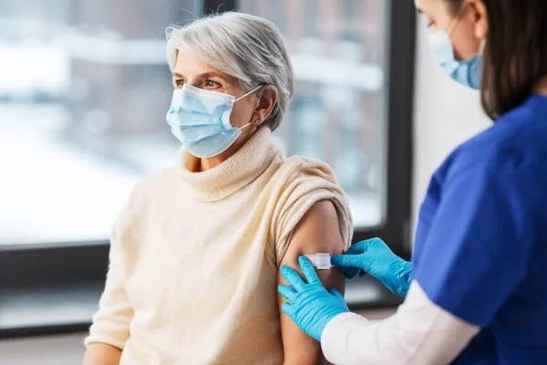 Verpleegkundige die medische pleisters op gevaccineerde vrouwen aanbrengt — Stockfoto
