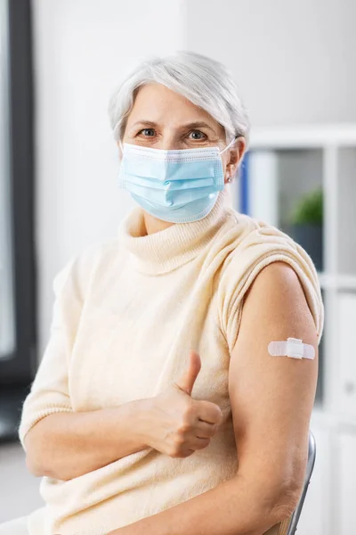 Gevaccineerde vrouw met masker met medische pleister op de arm — Stockfoto